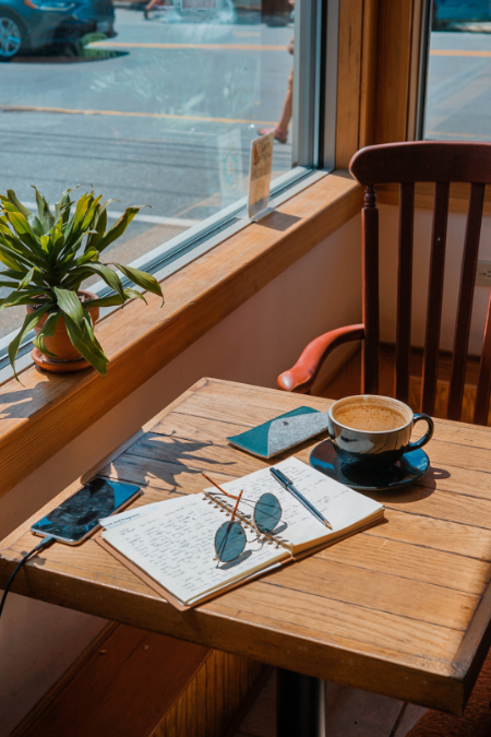 a table next to a window with a notebook on the table